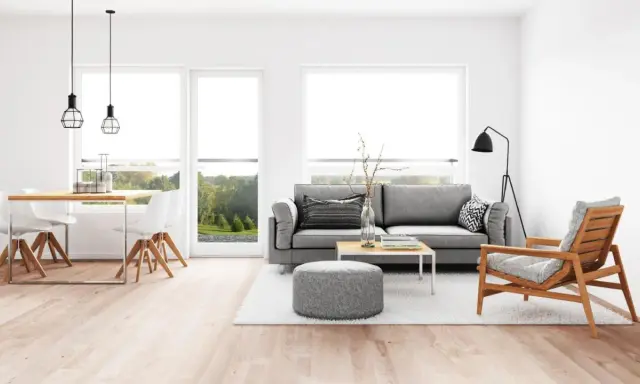 Elegante salón comedor con sofá gris, mesa de centro y sillas blancas. La iluminación es clave para combinar lamparas salon comedor, con colgantes sobre la mesa y una lámpara de pie.