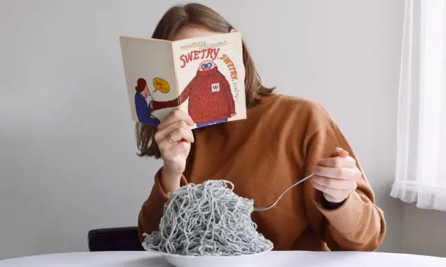 Dziewczyna czyta książkę o swetrach, jedząc spaghetti z włóczki. Jak znaleźć początek włóczki?
