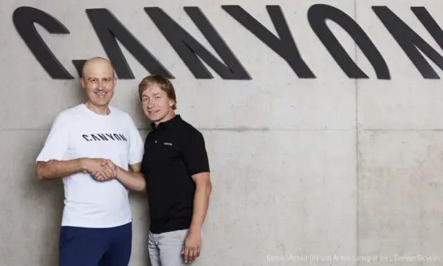 Roman Arnold und Armin Landgraf schütteln sich die Hände vor dem Canyon-Logo.