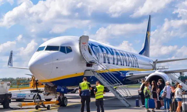 Samolot Ryanair na płycie lotniska z pasażerami i obsługą.