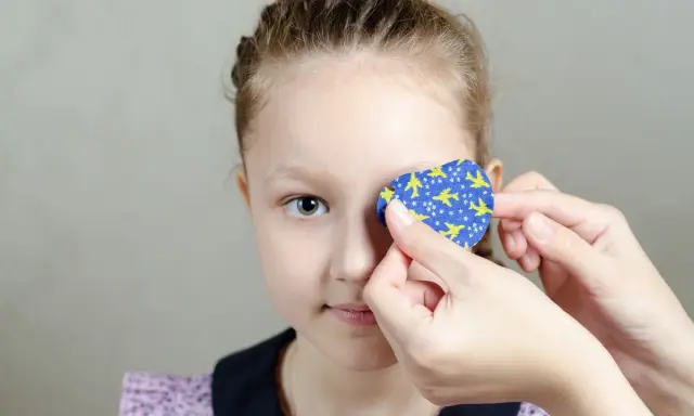 Dziecko z astygmatyzmem zakłada plaster na oko. Kiedy okulary nie wystarczają, taka metoda pomaga wzmocnić wzrok.