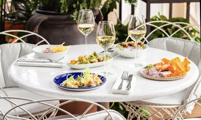 Delicioso brunch con niños en Madrid. Mesa con varios platos, copas de vino blanco y sillas blancas.