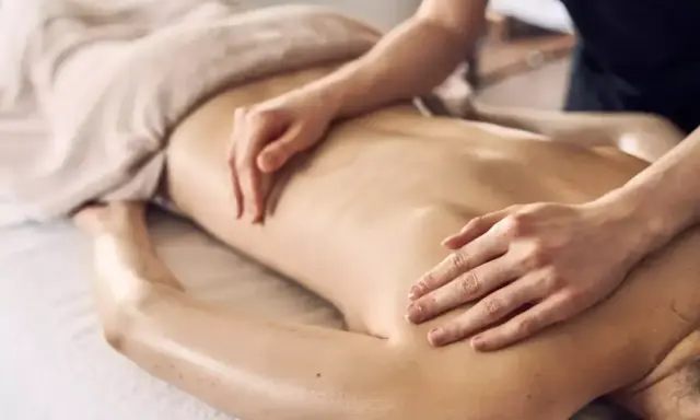 Dłonie terapeuty wykonują relaksacyjny masaż pleców, przynosząc ukojenie i odprężenie.