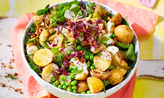 Kartoffelsalat mal anders: Ein bunter Mix aus kleinen Kartoffeln, Erbsen, Radieschen, Zwiebeln und Kräutern in einer Schüssel.