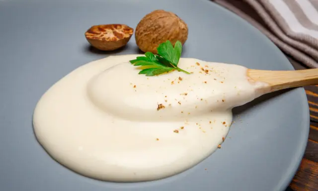 Krämig bechamelsås på en tallrik, med muskotnötter och persilja. Perfekt för ditt bechamelsås recept.