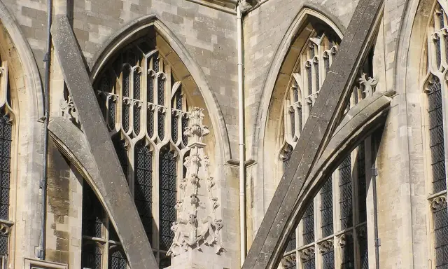 Detalle arquitectónico de una catedral gótica, mostrando la intrincada red de contrafuertes y arbotantes que sostienen sus imponentes muros y ventanas.