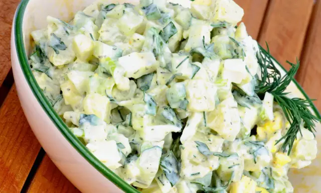 Kartoffelsalat mit Joghurt, Eiern und Gurken, garniert mit Dill. Ein cremiger und erfrischender Salat.