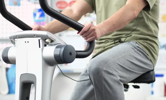 Osoba ćwiczy na rowerku stacjonarnym. Dowiedz się, ile jeździć na rowerku stacjonarnym, aby osiągnąć swoje cele.