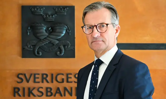 Erik Thedéen, med Riksbankens emblem bakom sig, ser ut som en person som vet hur man hanterar barn och ekonomi.
