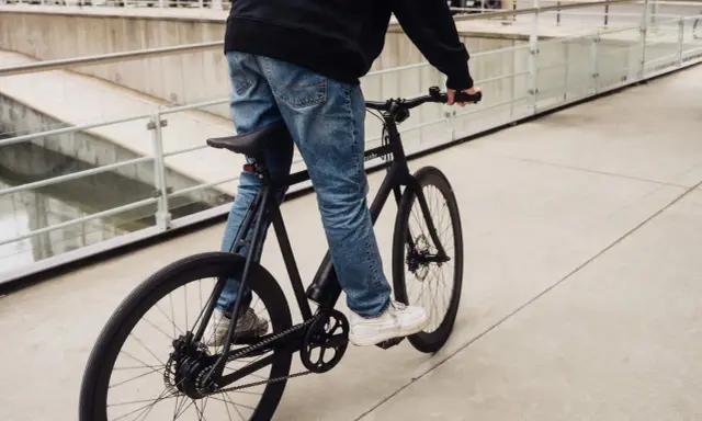 Ein Mann fährt ein schwarzes Fahrrad. Die Marke "sushi" ist auf dem Rahmen zu sehen. Die Nachricht "vanmoof insolvent" hallt nach.