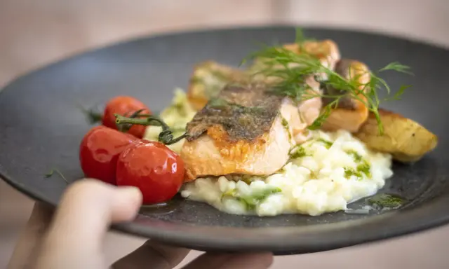 En läcker laxfilé med krämig risotto, körsbärstomater och dill. En perfekt rätt att njuta av, som en del av en **white guide Dalarna**-upplevelse.