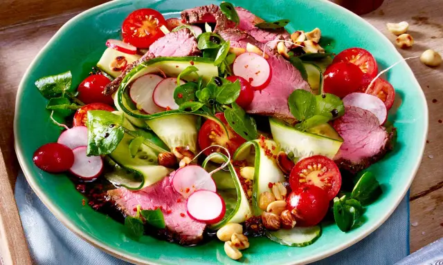 Saftiger Rinderbraten auf einem bunten low carb salat mit Gurke, Radieschen und Kirschtomaten. Nüsse sorgen für Crunch.