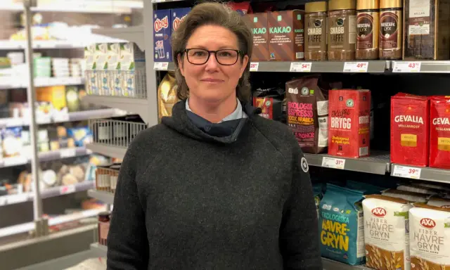 Kvinna i mataffär, redo för en matresa i Sverige. Hyllorna är fyllda med kaffe, havregryn och andra svenska matvaror.