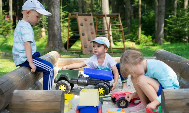 Dzieci bawią się w piaskownicy, ucząc się, jak pomóc dziecku być lubianym przez zabawę i dzielenie się zabawkami.