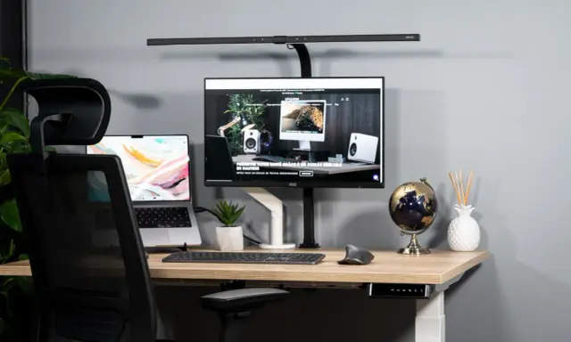 Bureau moderne avec un écran ergonomique, un ordinateur portable et une chaise de bureau.