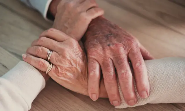 Mains âgées se tenant, symbolisant le soutien et l'amour, même face à un conjoint narcissique.