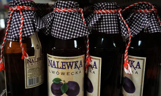 Butelki nalewki lwóweckiej z etykietami i ozdobnymi sznurkami.