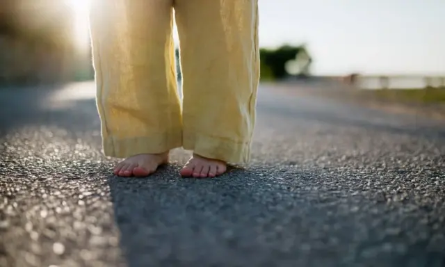 Barfuß auf Asphalt, die weite Leinenhose im Abendlicht. Ein Gefühl von Freiheit, als ob die Hose frisch gewaschen wäre und bereit für neue Abenteuer.