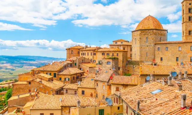 Panoramica di Volterra, con le sue case in pietra e tetti in cotto, che si estende verso le colline toscane, ricordando la bellezza di San Gimignano.