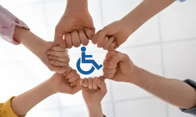Dłonie tworzą krąg wokół symbolu niepełnosprawności, symbolizując wsparcie i integrację.