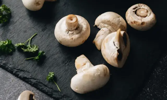 Świeże pieczarki na czarnej desce. Zastanawiasz się, czy pieczarki można mrozić? Tak, można je mrozić, zachowując ich smak i aromat.