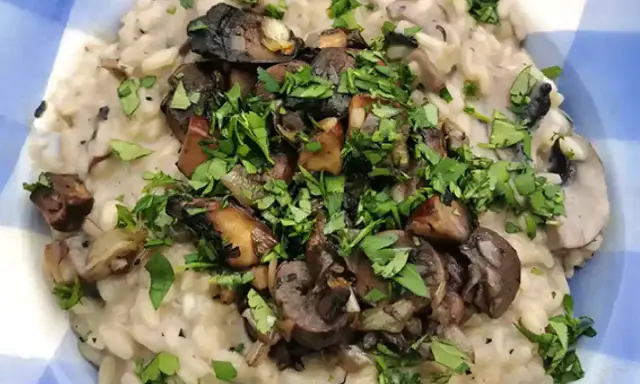 Delicioso risotto de setas cremoso, coronado con champiñones salteados y perejil fresco picado.