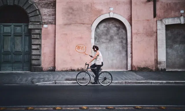 Un ciclista con cuffie ascolta musica mentre pedala, un'istantanea dal reportage di un tour urbano.