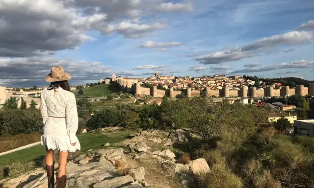 Mujer con sombrero y botas de cowboy admira las murallas de Ávila, un lugar perfecto para visitar con niños.