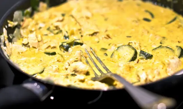 Pyszne curry z cukinią i kurczakiem w kremowym sosie, gotowe do podania. Widelec czeka na pierwszy kęs.