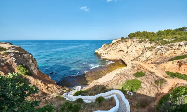 Treppe führt zum malerischen Algarve Meer. Felsformationen und türkisfarbenes Wasser.