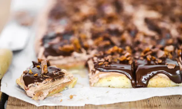 En chokladkaka i långpanna med fluffig chokladkräm och glansig chokladglasyr, toppad med krossad choklad och bitar av godis.