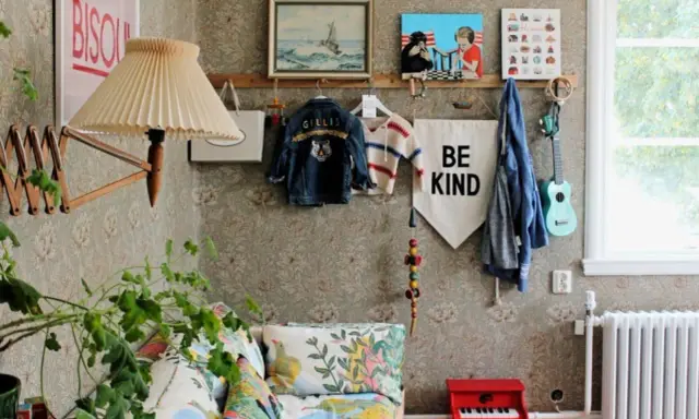 En mysig vrå med barnkläder, en gitarr och en "Be Kind"-flagga, inspirerad av Johanna Bradford blogg.