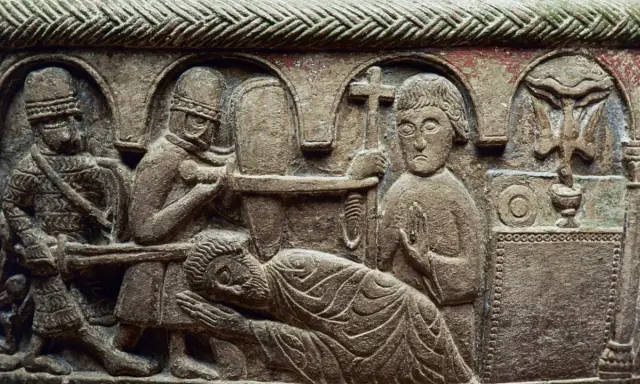 Detaljerad stenrelief från medeltiden konst visar en dramatisk scen med soldater och en liggande figur. En man håller ett kors.