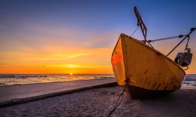 Żółta łódź na plaży w Niechorzu podczas zachodu słońca. Piękne niechorze atrakcje nad morzem.