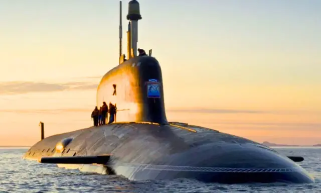 Un imposant sous-marin, potentiellement le sous-marin le plus puissant du monde, navigue sur une mer calme au coucher du soleil.