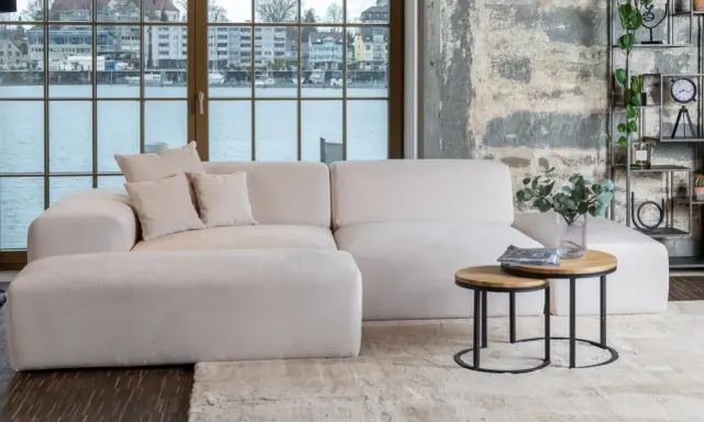 Un tavolino rotondo in legno e metallo con riviste e un vaso di eucalipto: idee per cosa mettere sul tavolino del salotto.