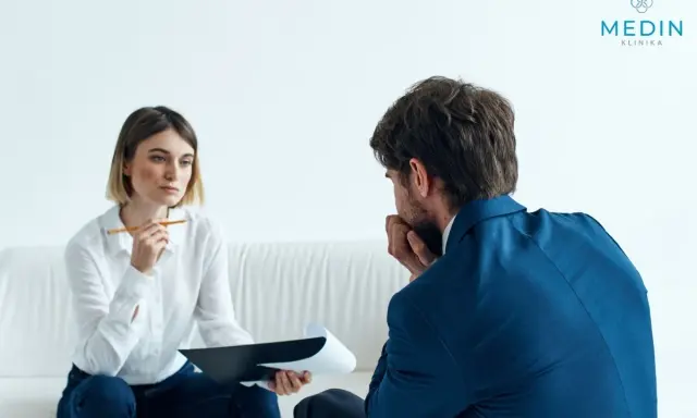 Kobieta z notatkami i mężczyzna w garniturze rozmawiają. Tak wygląda psychoterapia: wsparcie i zrozumienie w trudnych chwilach.