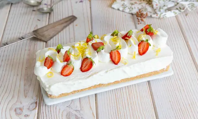 Cheesecake citron facile rapide, garni de fraises fraîches et de zestes de citron. Un délice crémeux et acidulé.