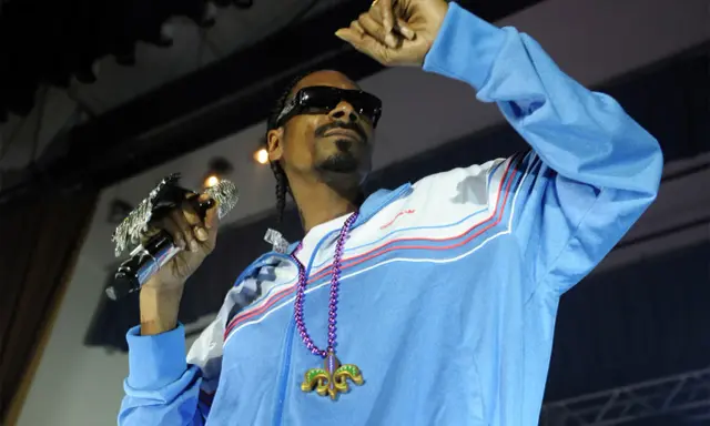 Snoop Dogg w błękitnej bluzie z naszyjnikiem, trzymający mikrofon. Ile pali? Tego nie wiemy, ale na pewno daje czadu na scenie!