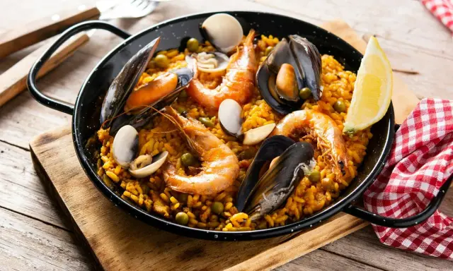 Pyszna paella z owocami morza, idealna do przygotowania z ryżem bomba. Krewetki, małże i cytryna dopełniają danie.