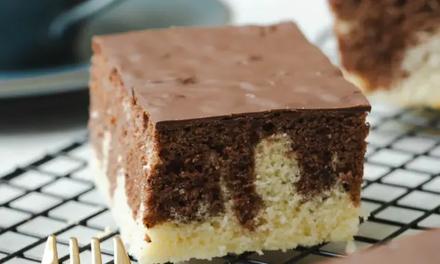 Ein Stück saftiger Marmorkuchen vom Blech, mit Schokoladenglasur, auf einem Kuchengitter.