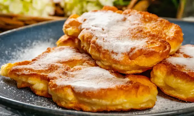 Délicieux Apfelkiechle saupoudrés de sucre glace sur une assiette bleue. Une recette gourmande à essayer !