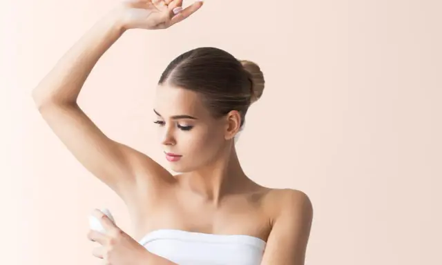 Donna applica deodorante sotto l'ascella. Si discute se l'aluminum chlorohydrate fa male.