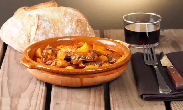 Un plato de all i pebre, con pan rústico y vino tinto, listo para disfrutar.