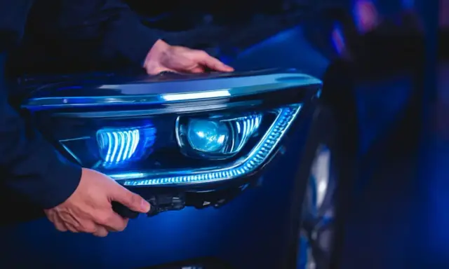Man installing a modern LED headlight assembly, upgrading from halogen.