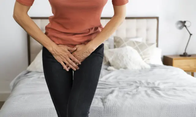 Mujer con las manos en el abdomen, sintiendo dolor de ovarios antes de la regla.