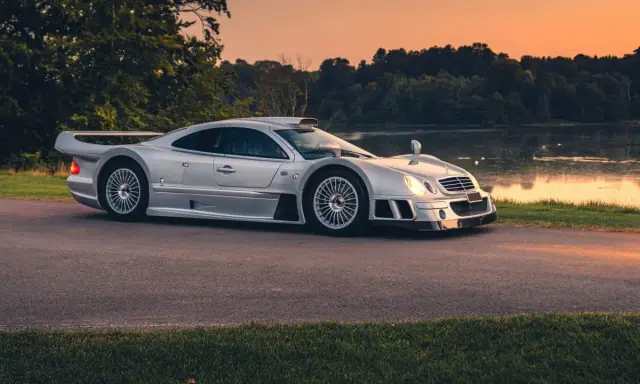 Silberner Mercedes CLK GTR am Seeufer bei Sonnenuntergang. Ein Blick auf dieses seltene Sammlerstück, das den Begriff "Mercedes CLK GTR Preis" neu definiert.