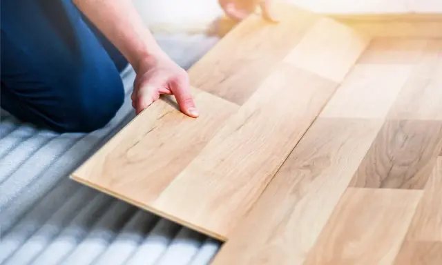Man colocando una tabla de madera para poner suelo de tarima flotante.