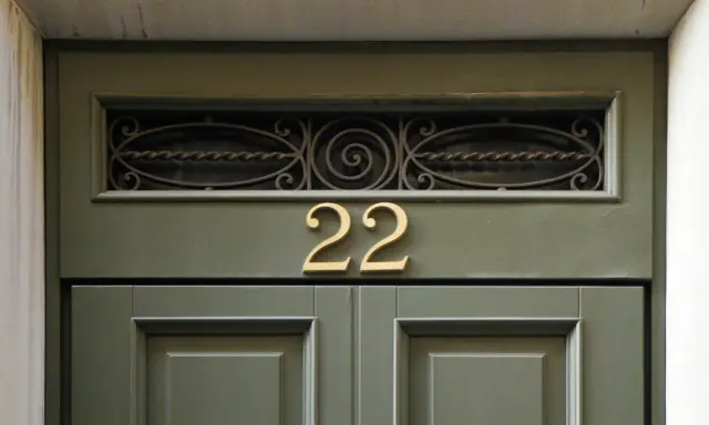 Złote **anielskie liczby** 22 na zielonych drzwiach.