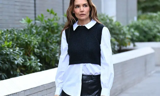 Donna con camicia bianca e gilet nero, la camicia dentro i pantaloni di pelle nera.